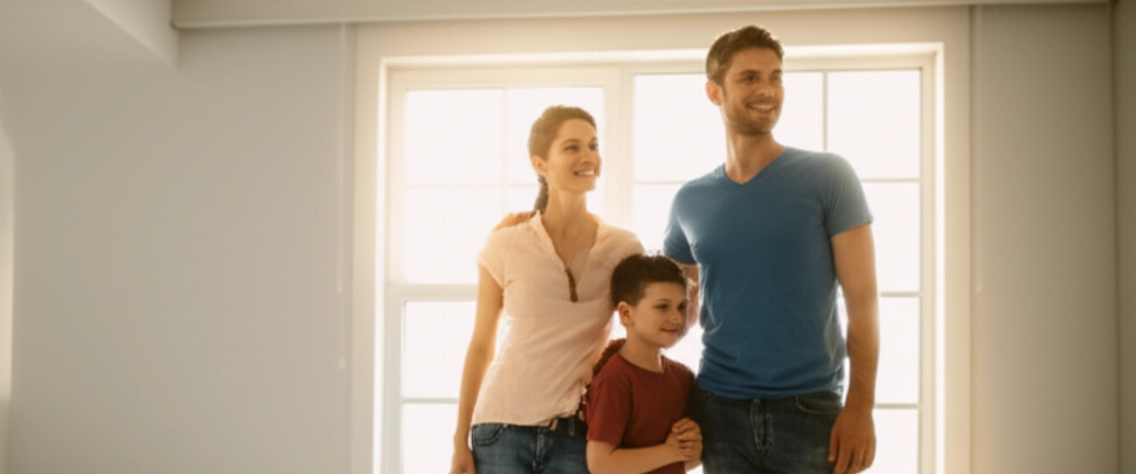 Eine glückliche kaukasische Familie lächelt in einem hellen Raum ihres neuen Zuhauses, was einen erfolgreichen Umzug und einen Neuanfang symbolisiert.